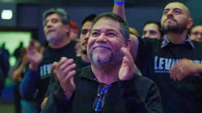 A man clapping and smiling in the audience.