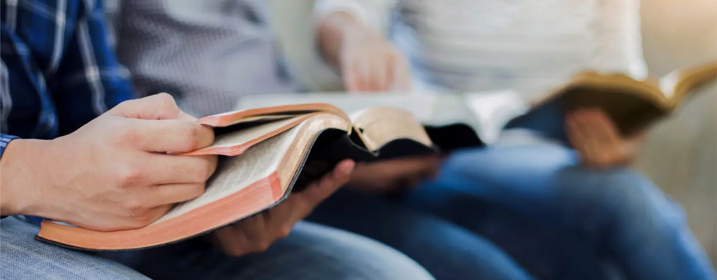 Two people sitting down together read their Bibles. 